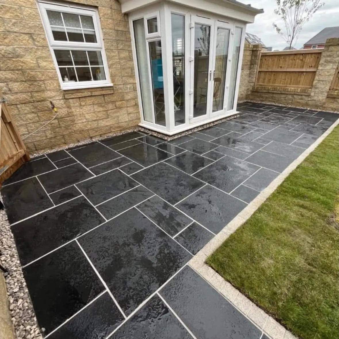 Black Indian stone patio with white pointing beside a lawn